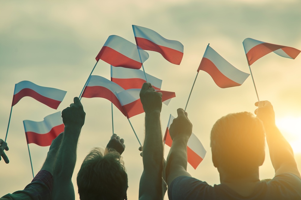 ludzie z flagami Polski w rękach grupa ludzi machająca polskimi flagami
