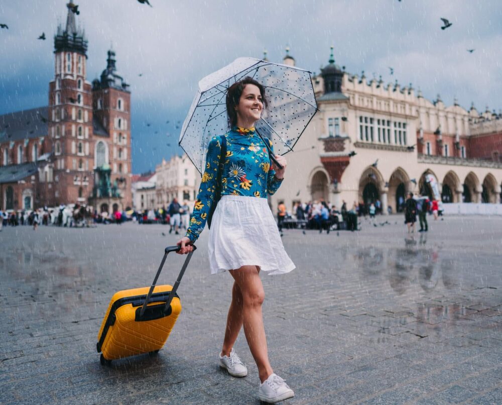 dziewczyna z parasolem idąca przez krakowski rynek