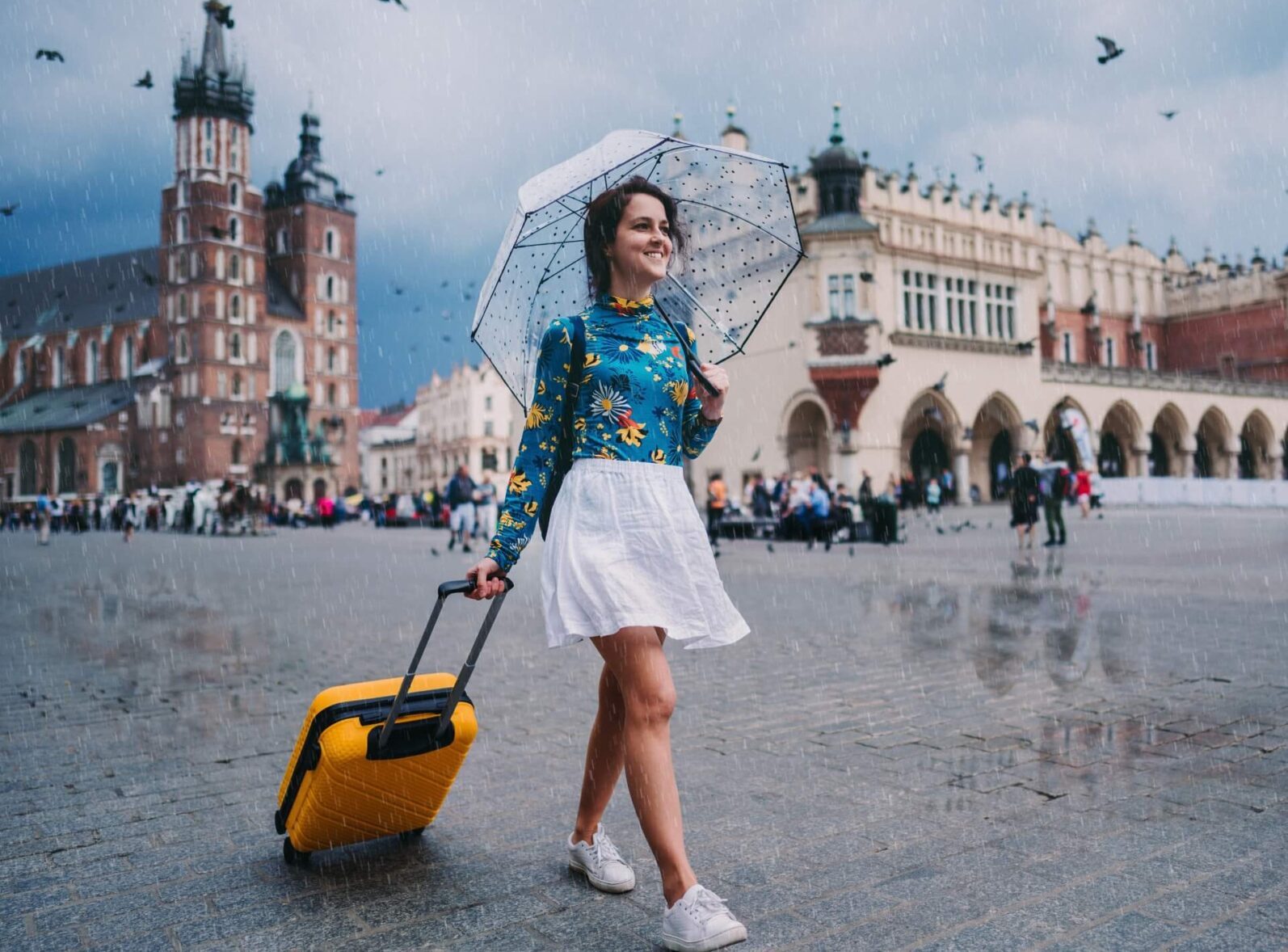 dziewczyna z parasolem idąca przez krakowski rynek