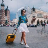 dziewczyna na Rynku Głównym w Krakowie z walizką w deszczu dziewczyna z parasolem idąca przez krakowski rynek